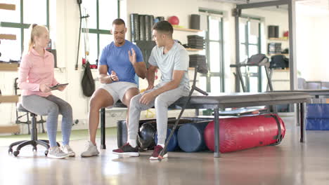 physical therapist discussing rehabilitation exercises with two men in gym