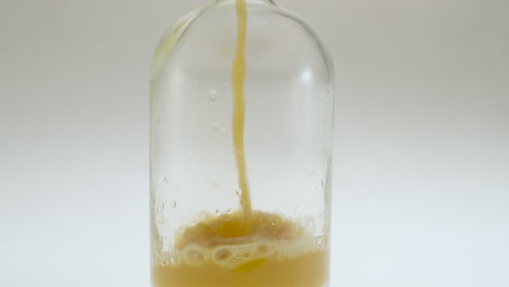 close up shot of pouring apple juice into a glass bottle