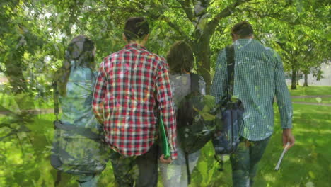 composite video of close up of leaves against rear view of group of people walking in the garden