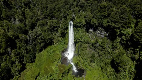 Carro-Aéreo-Bajando-En-La-Cascada-Salto-El-León-Cayendo-En-Una-Piscina-Rocosa-Rodeada-De-Bosques-Verdes,-Pucón,-Chile