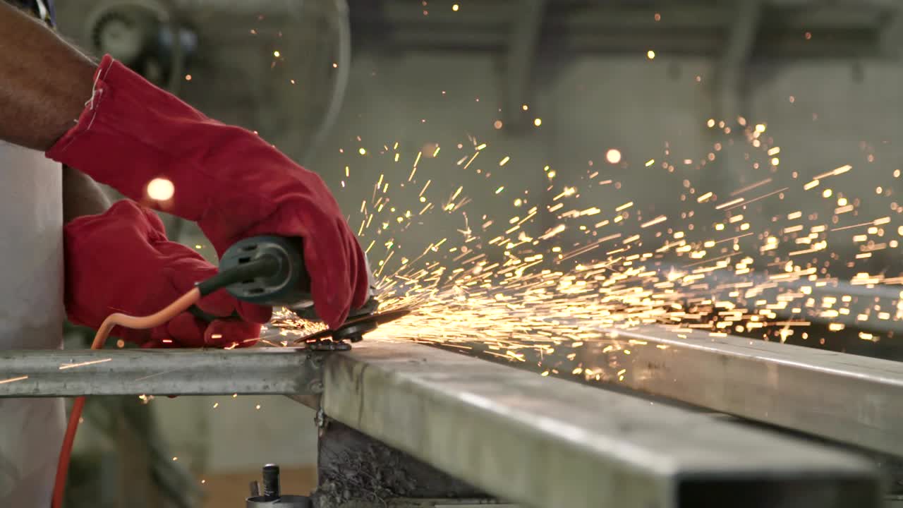 movimiento lento de un trabajador usando un molinillo de metal con chispas volando en una tienda de metal