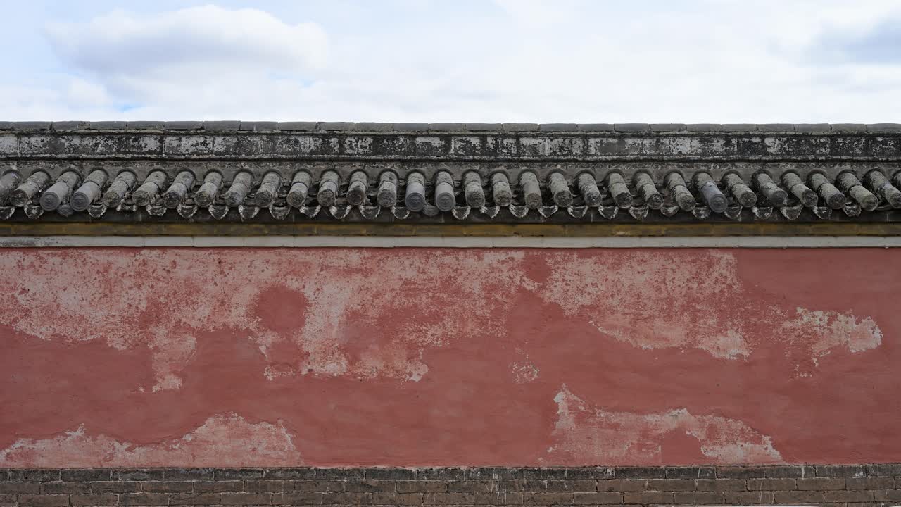 Close-up of a weathered red wall at Erdene Zuu Monastery. The peeling paint and grey roof tiles highlight the historic texture and resilience of Mongolia's oldest Buddhist site