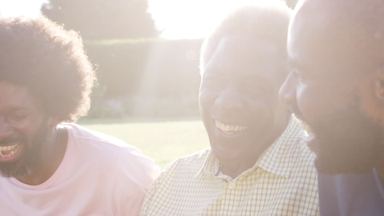 Senior black man laughing with his two adult sons, close up