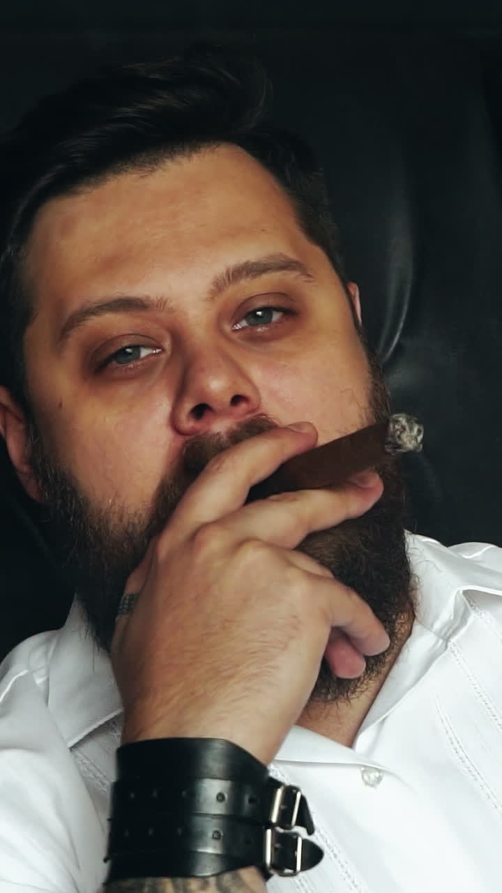 Man smoking cigar. Side view of bearded stylish man with a cigar