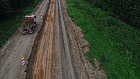 High-angle-shot-over-a-white-truck-carrying-soil-after-excavation-work-and-driving-away-over-under-construction-work-at-daytime