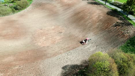 a tractor working in a field, driving uphill among the trees of the forest seen from a drone's perspective