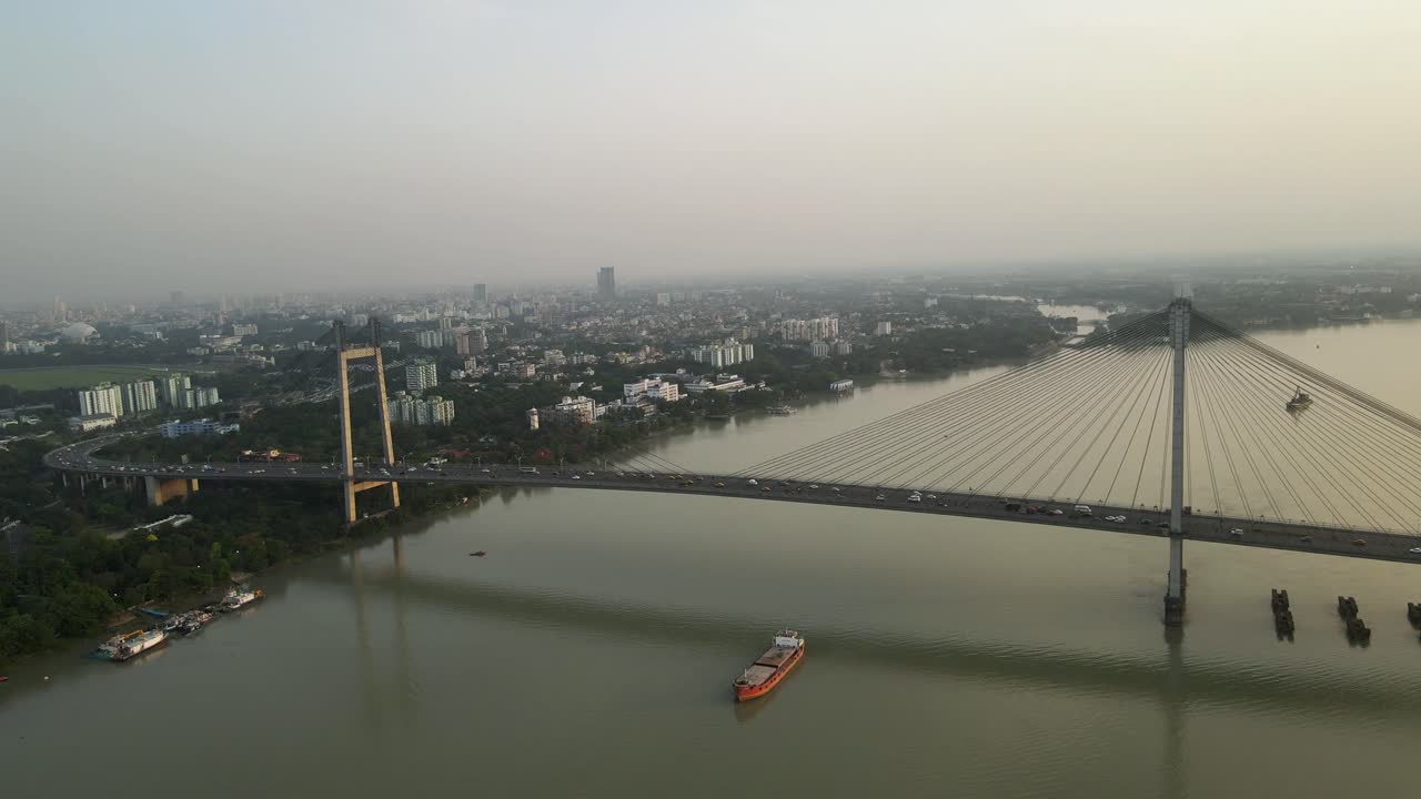 Aerial drone capture of Vidyasagar Bridge during sunset, city lights twinkling over the tranquil river.