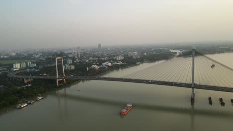 aerial drone capture of vidyasagar bridge during sunset, city lights twinkling over the tranquil river.