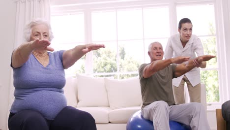 Smiling-nurse-helping-senior-couple-doing-exercises