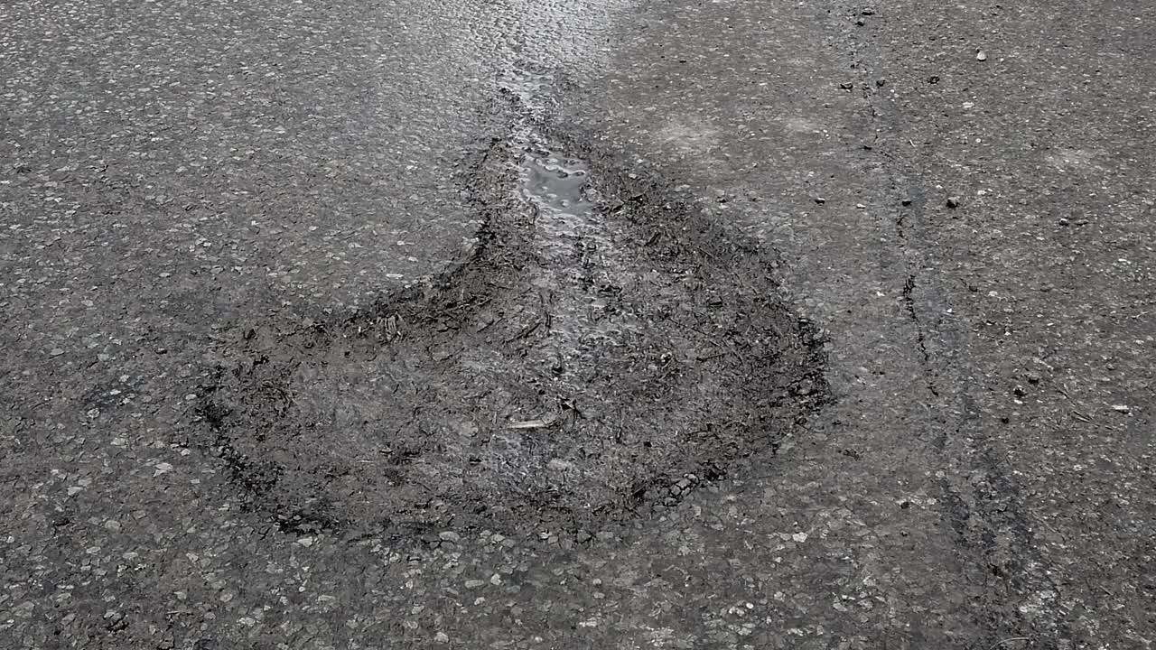 Large pothole in a rural road which caused a near fatal accident in the county of Rutland in England, United Kingdom