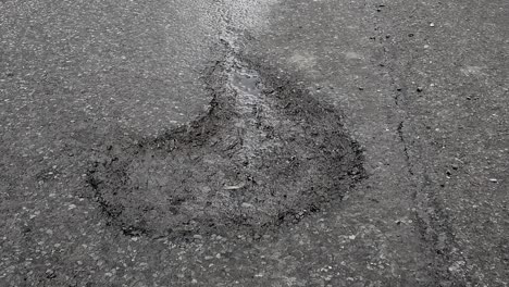 large pothole in a rural road which caused a near fatal accident in the county of rutland in england, united kingdom