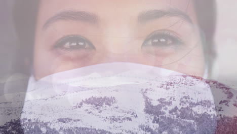 digital composition of portrait of woman wearing face mask against winter landscape