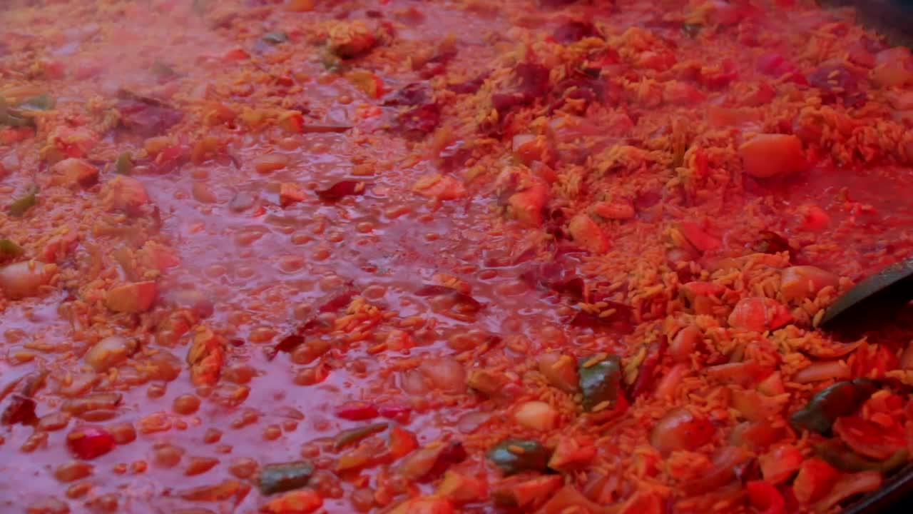 Paella cooking and bubbling in a large pan at a street food market.