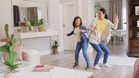 video of happy asian mother and daughter dancing in living room