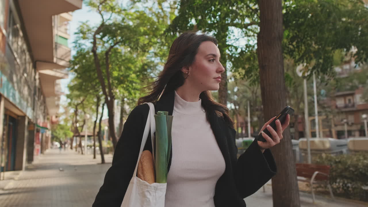 Donna che cammina per strada in città usando il telefono