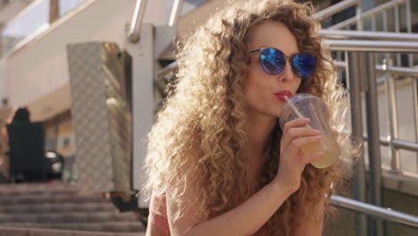 mujer con cabello rizado bebiendo batido al aire libre