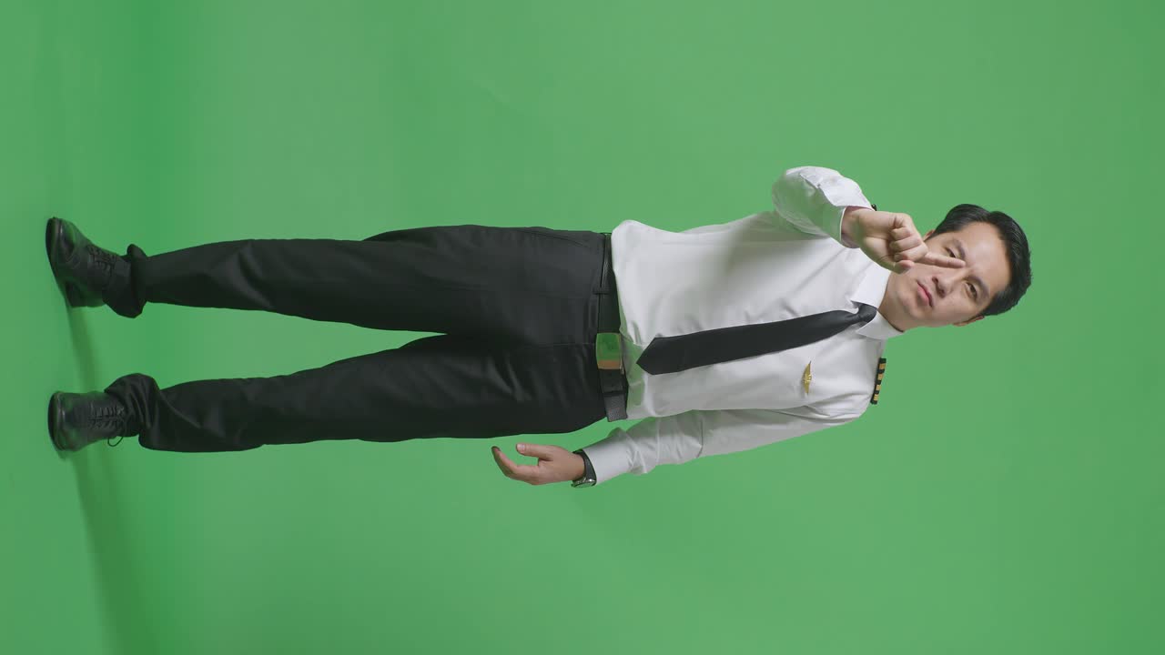 동양인 남자 조종사가 당신을 가리키고 낙서 손가락 표시 없이 녹색 스크린 배경 스튜디오에서 불쾌감을 표합니다.