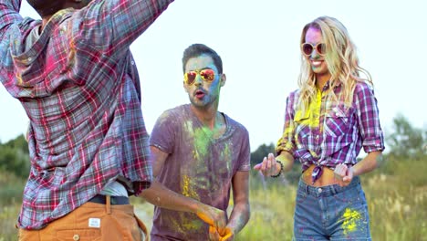 mixed races young male and female people dancing and having fun with colorful paints during holi festival