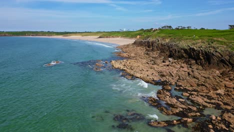 backward drone movement from the blancs-sablons cove coastal with rocky promontory jutting into turquoise sea, le conquet, brittany, france