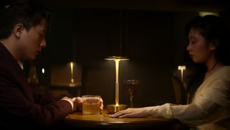 a couple in a dimly lit bar, sharing a tense moment with the woman about to leave after returning her wedding ring