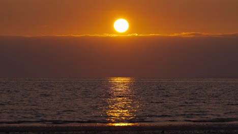 Toma-En-Cámara-Lenta-De-Una-Vibrante-Puesta-De-Sol-Sobre-El-Océano-En-El-Horizonte