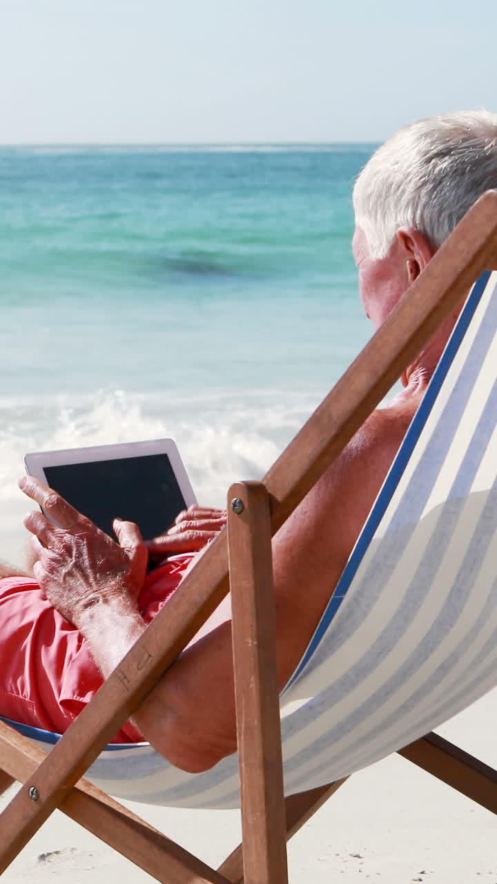 Retired old man using tablet while lying on deckchair