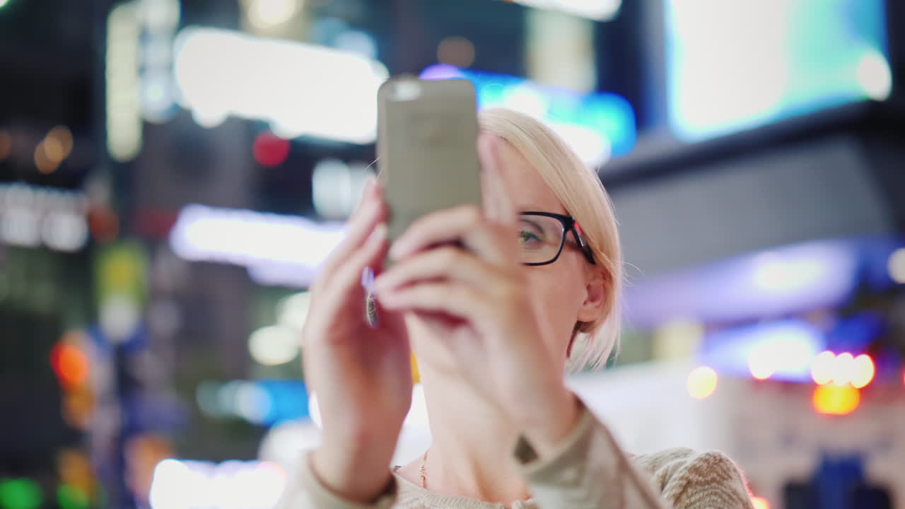 mujer filmando ciudad de noche