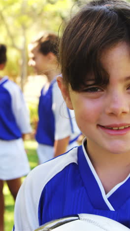 chica sonriente sosteniendo un balón de fútbol en el parque