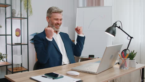 business man winner working browsing typing on laptop at office celebrate big lottery win good news