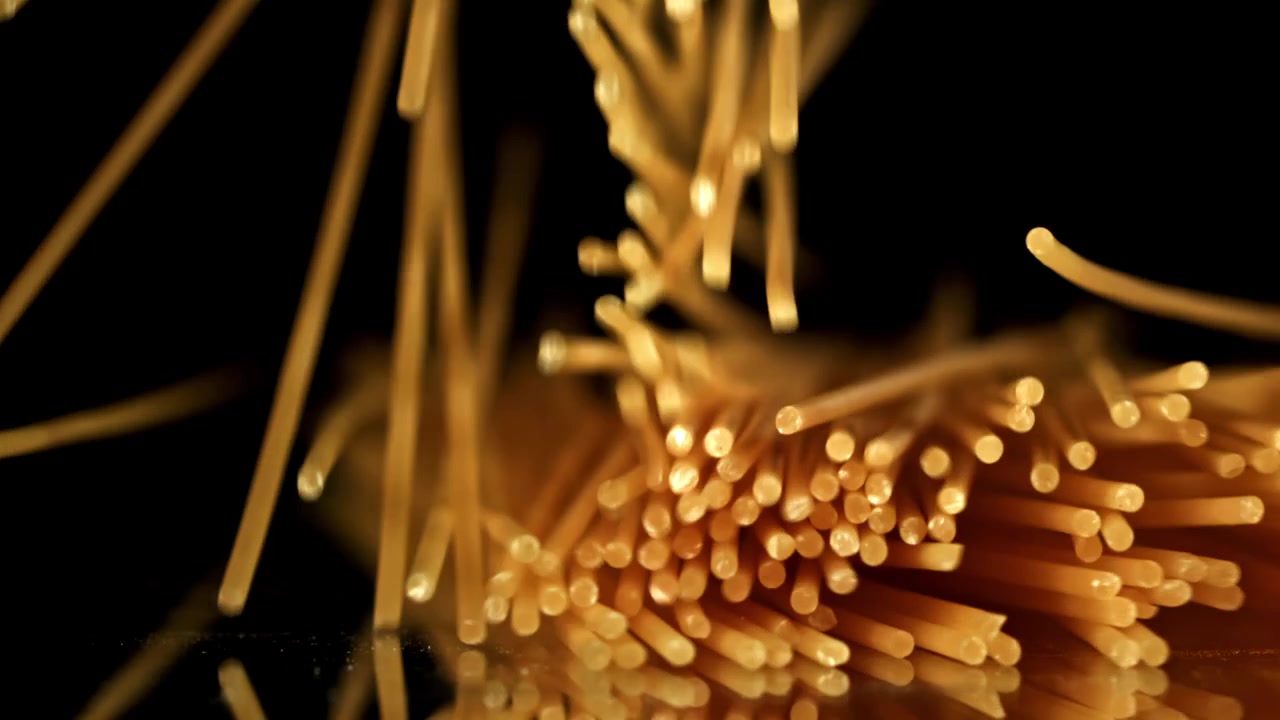 Spaghetti crudi che cadono al rallentatore su sfondo nero