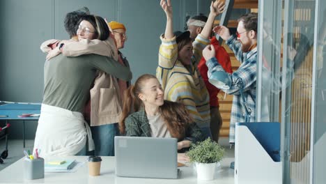 happy businesspeople hugging doing high-five and laughing sharing positive emotions in modern office