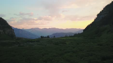 Beautiful-Drone-Shot-flying-smoothly-through-a-mountain-meadow-towards-a-colorful-sunrise