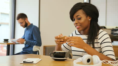 hermosa mujer afroamericana tomando café y usando un teléfono inteligente