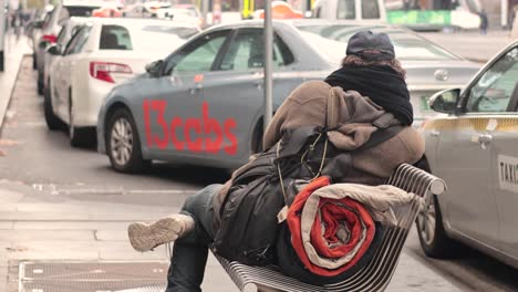 man sitting on bench with belongings