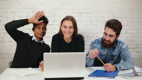 Feliz-Y-Atractivo-Grupo-étnico-Mixto-De-Jóvenes-Profesionales-Sonriendo-Y-Agitando-Las-Manos-Mientras-Saludan-A-Su-Colega,-Teniendo