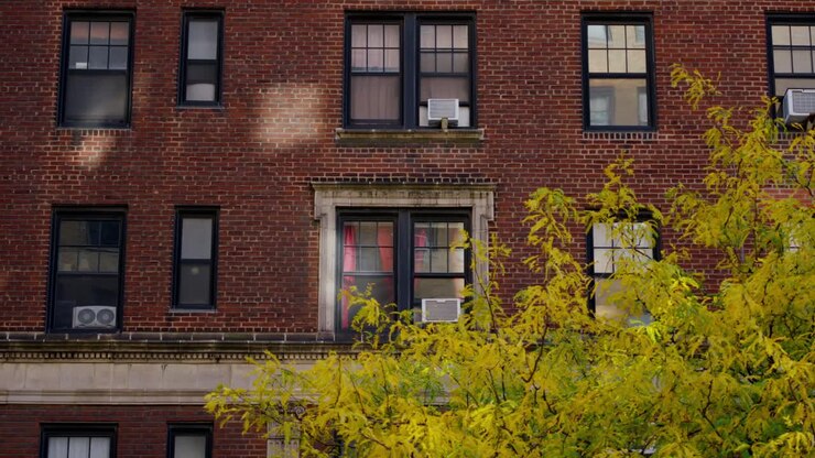 Scena autunnale di un tradizionale edificio di appartamenti in mattoni rossi con foglie gialle nel cortile antistante, New York, New York, Stati Uniti