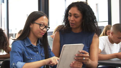 Teacher-helping-teenage-schoolgirl-with-tablet-computer