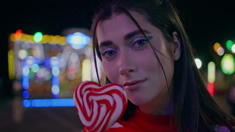 beautiful girl holding lollipop at funfair closeup. romantic female look camera