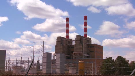 a power plant with striped towers with clouds moving behind