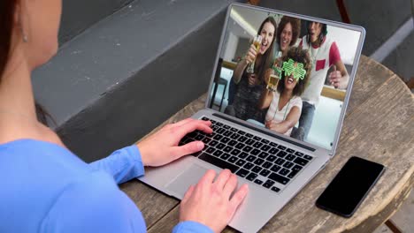 Caucasian-woman-at-home-using-laptop-making-video-call-on-st-patrick's-day