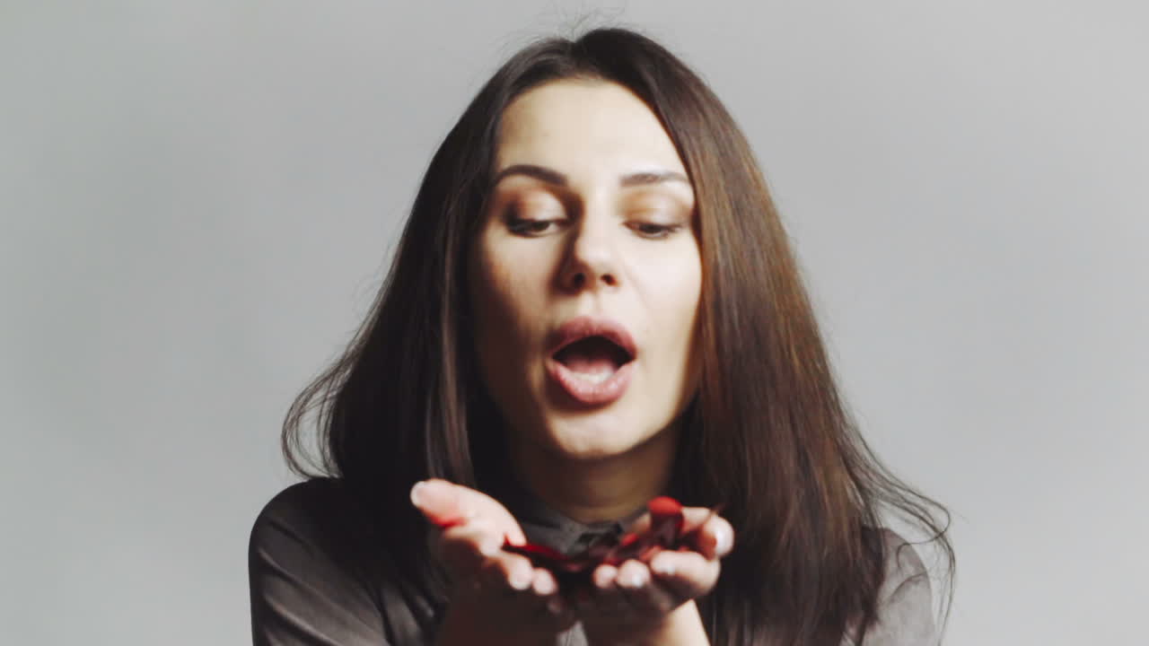Blowing confetti decorations. Girl blowing colorful confetti while posing for photography in studio