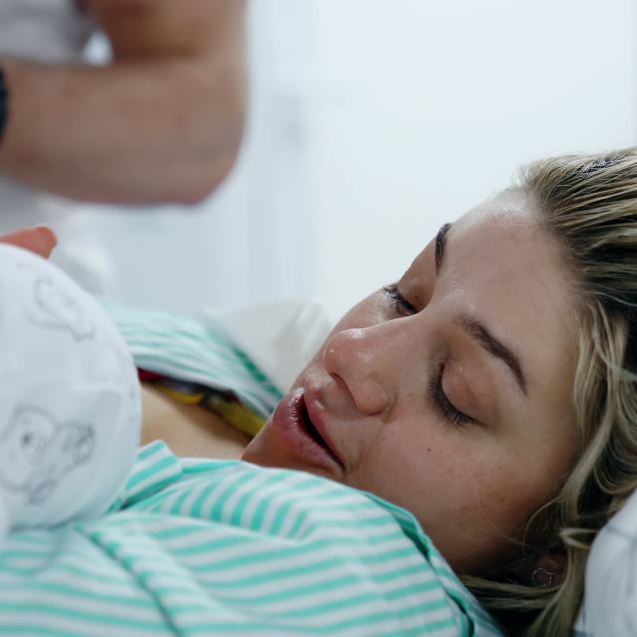 Happy new mom is caressing her baby being breastfed. Woman and child after the childbirth. Close up