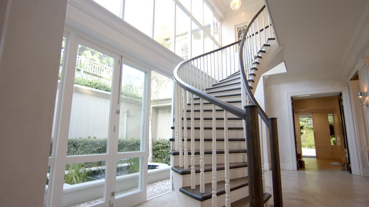 Sunlight flooding through large windows, illuminating elegant spiral staircase