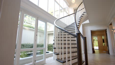 sunlight flooding through large windows, illuminating elegant spiral staircase