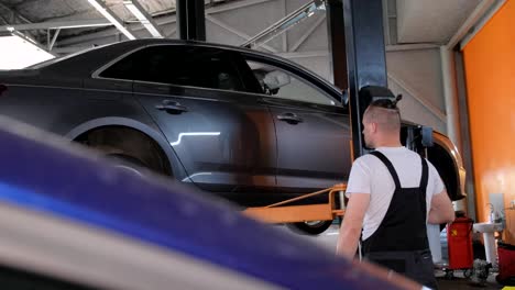 mechanic working on a car lifted in an auto repair shop