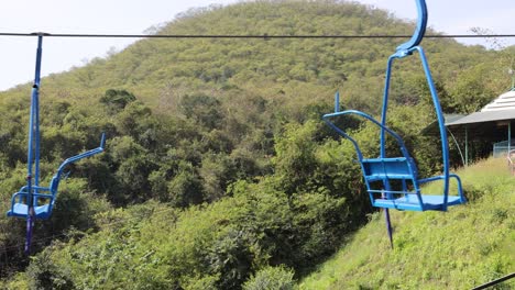 empty chairlifts moving over lush greenery