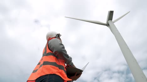 progressive engineer working with the wind turbine, with the sky as background.