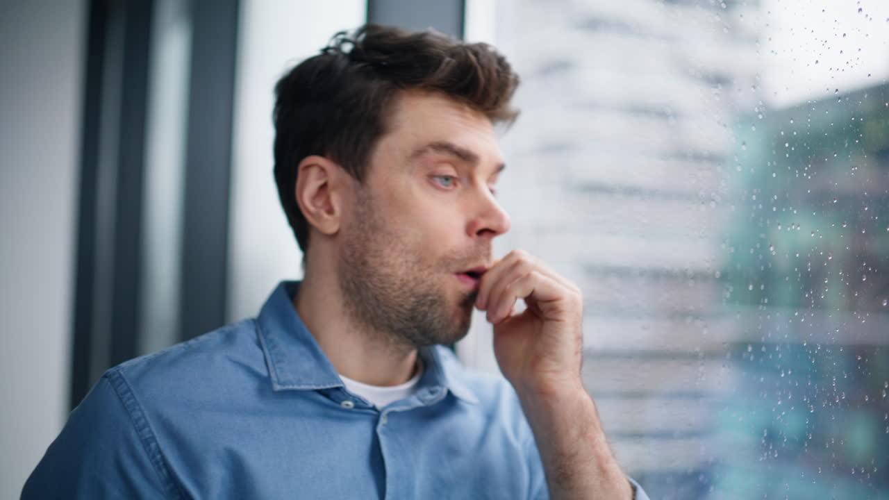 Worried employee finish cellphone conversation standing at window closeup