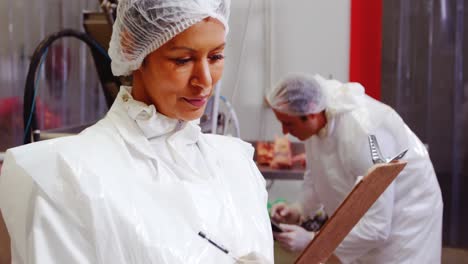 Female-butcher-writing-on-clipboard