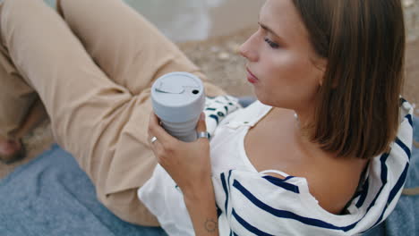 woman drinking picnic coffee on cliff edge closeup. pensive girl rest seashore